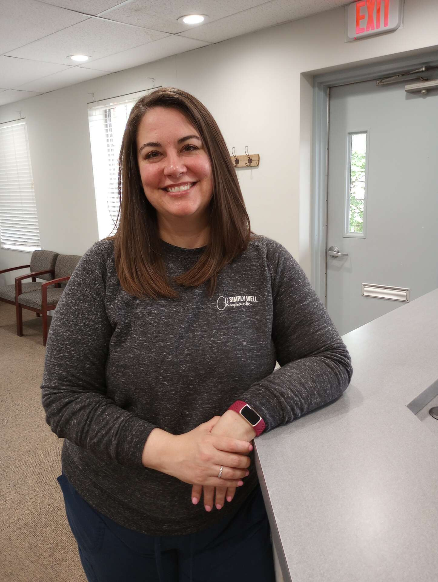 Dr. Faith Swartzendruber of Simply Well Chiropractic in Cincinnati leans against the counter, smiling.