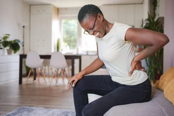 Woman wincing in pain while holding her lower back and hip, illustrating how non-invasive SoftWave therapy targets chronic hip and pelvic pain.