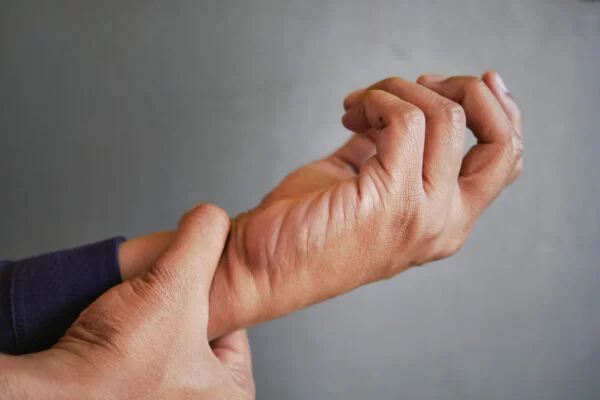 Close-up of a hand gripping a painful wrist joint, representing effective relief for wrist and hand pain with SoftWave therapy.