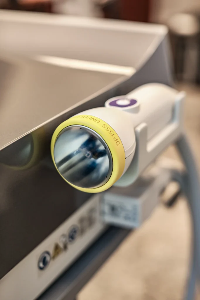 SoftWave Therapy Applicator handpiece with a yellow rim resting in its holder on a SoftWave Therapy console.